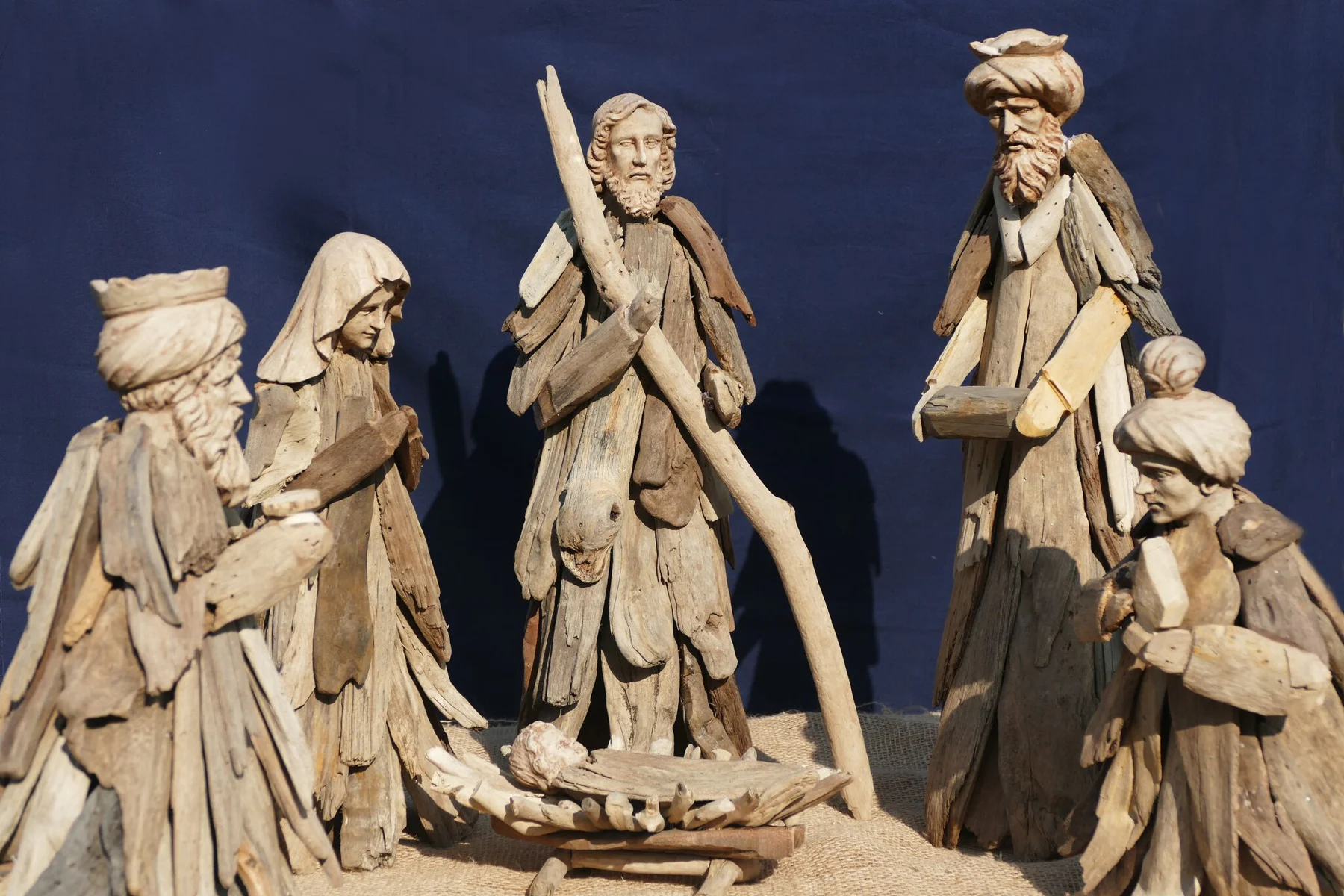 Krippenszene mit hellen, kantigen Figuren vor blauem Hintergrund