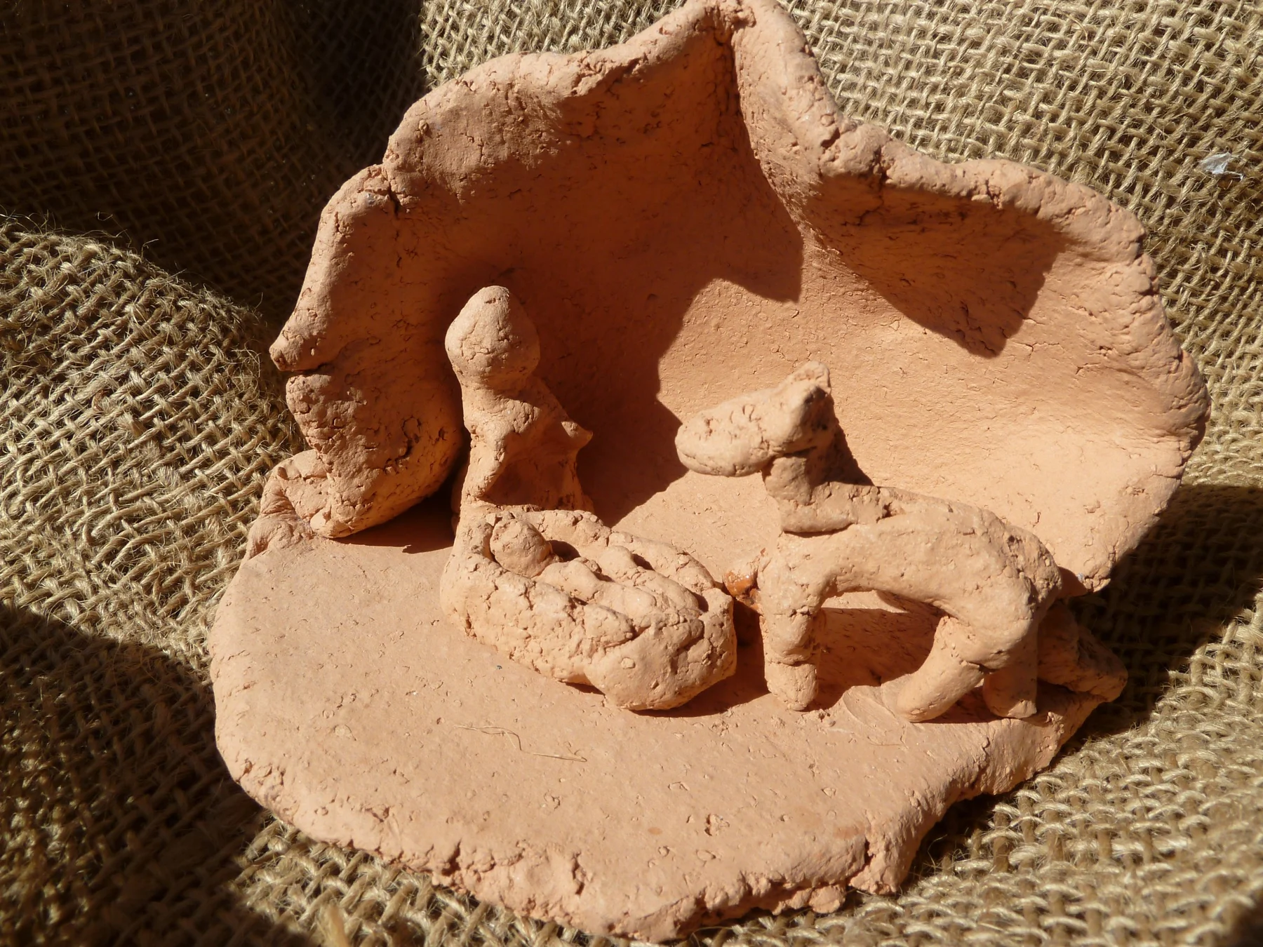Erdfarbene Krippe mit kleinen Figuren in einer offenen Höhle