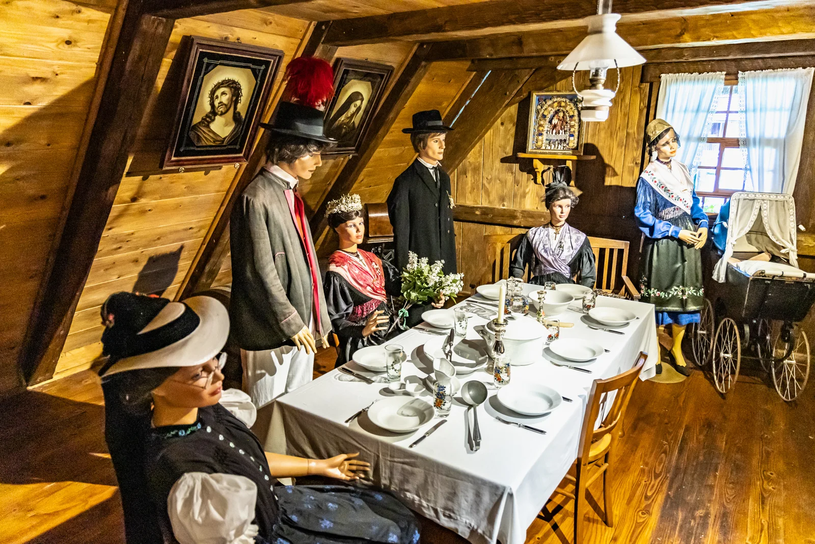 Museumsfiguren in Tracht rund um einen gedeckten Tisch in der holzgetäfelten Stube